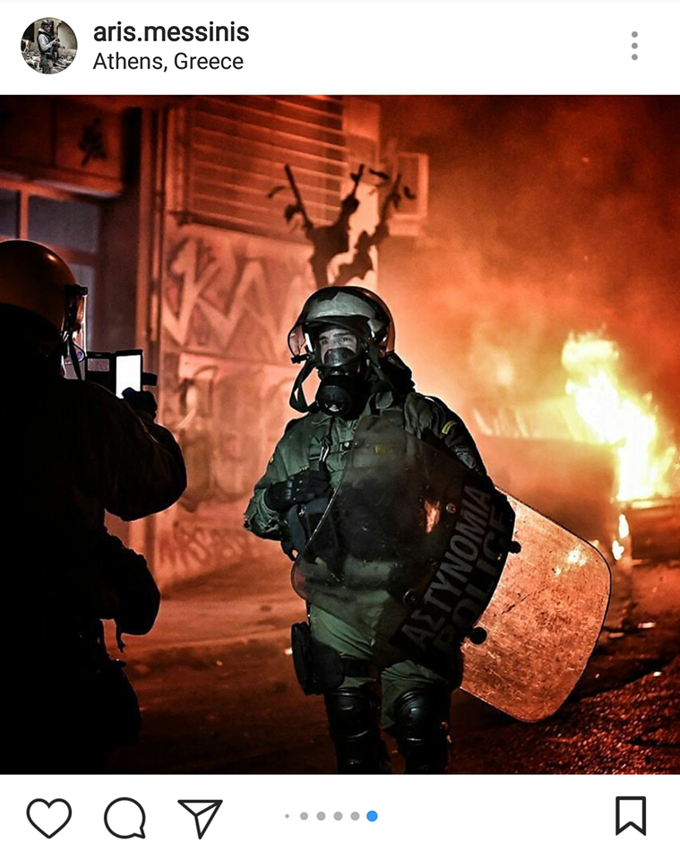Άνδρες των ΜΑΤ βγάζουν φωτογραφίες με φόντο την καμένη Αθήνα