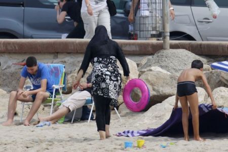 A Muslim woman wears a burkini, a swimsuit that leaves only the face, hands and feet exposed, on a beach in Marseille