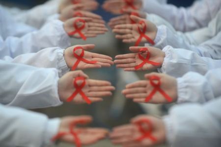Students hold red ribbons during an event to mark World AIDS Day at a medical college in Yangzhou
