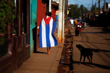 A dog barks at a person wearing a Cuban flag in the town of Alquizar