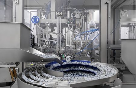 Ένα μηχάνημα από το εργοστάσιο της εταιρείας UNI-PHARMA κατά την διάρκεια της παραγωγής. Στο βάθος φαίνεται ένας εργαζόμενος της εταιρείας.