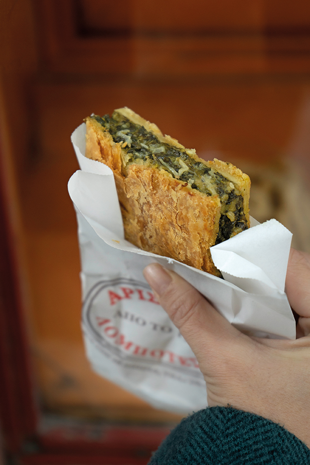 Ένα χέρι κρατάει μια χωριάτικη χορτόπιτα χωρίς αβγό και τυρί.